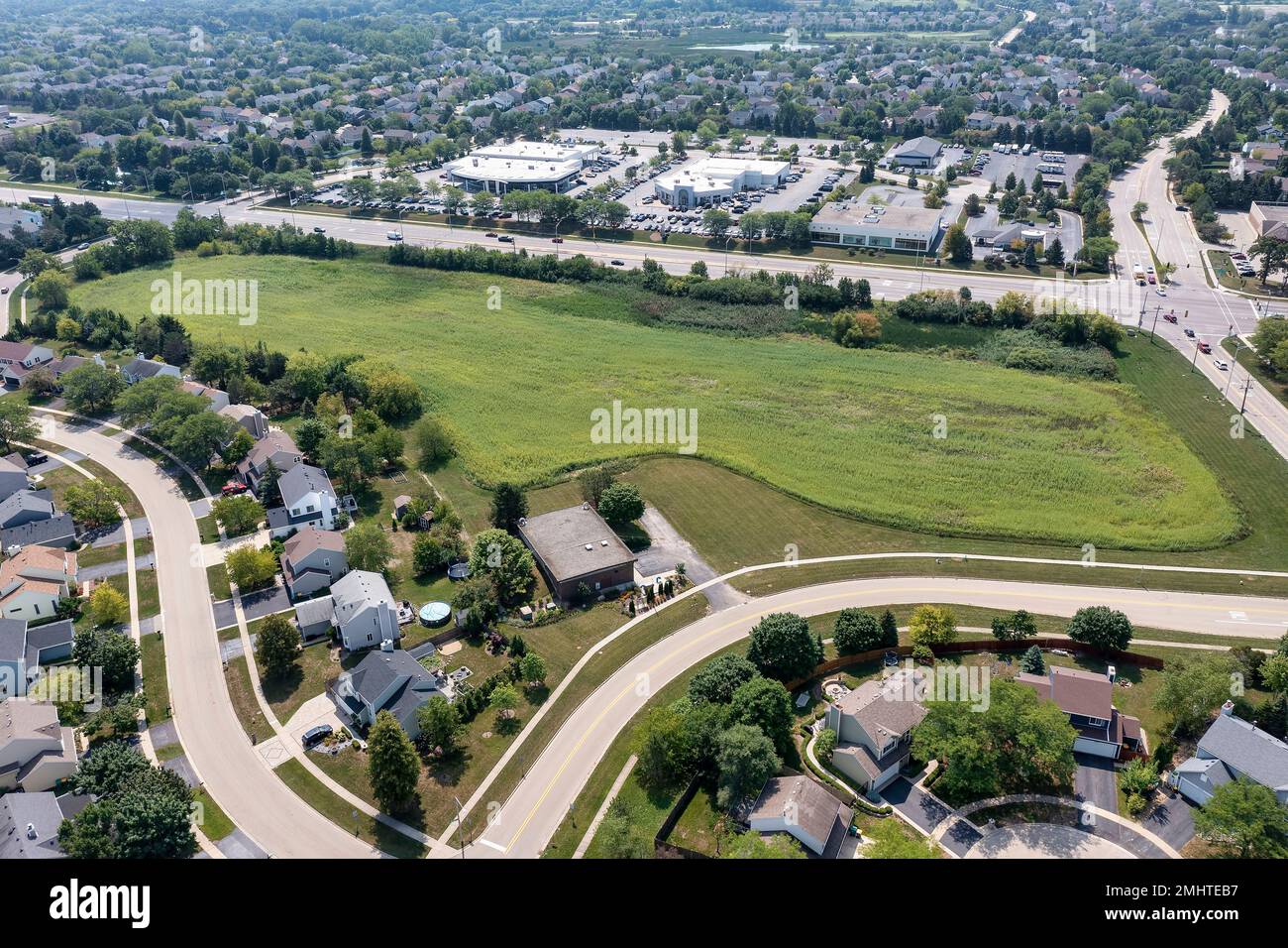 Une antenne montrant une parcelle de terrain en vente à proximité d'un centre de développement de logements et de commerces de détail dans une zone de banlieue. Banque D'Images