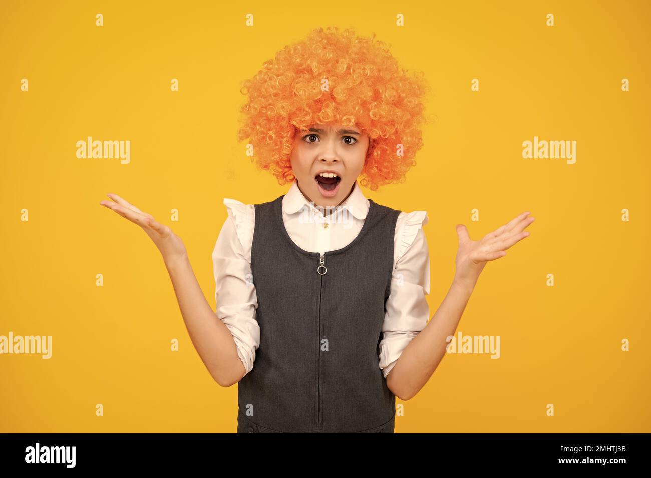 Fête d'anniversaire pour filles. Drôle d'enfant dans la perruque rouge curly. Temps de Amuse-toi bien. Jeune fille avec des cheveux orange, étant un clown. Face surprise, émotions surprise Banque D'Images