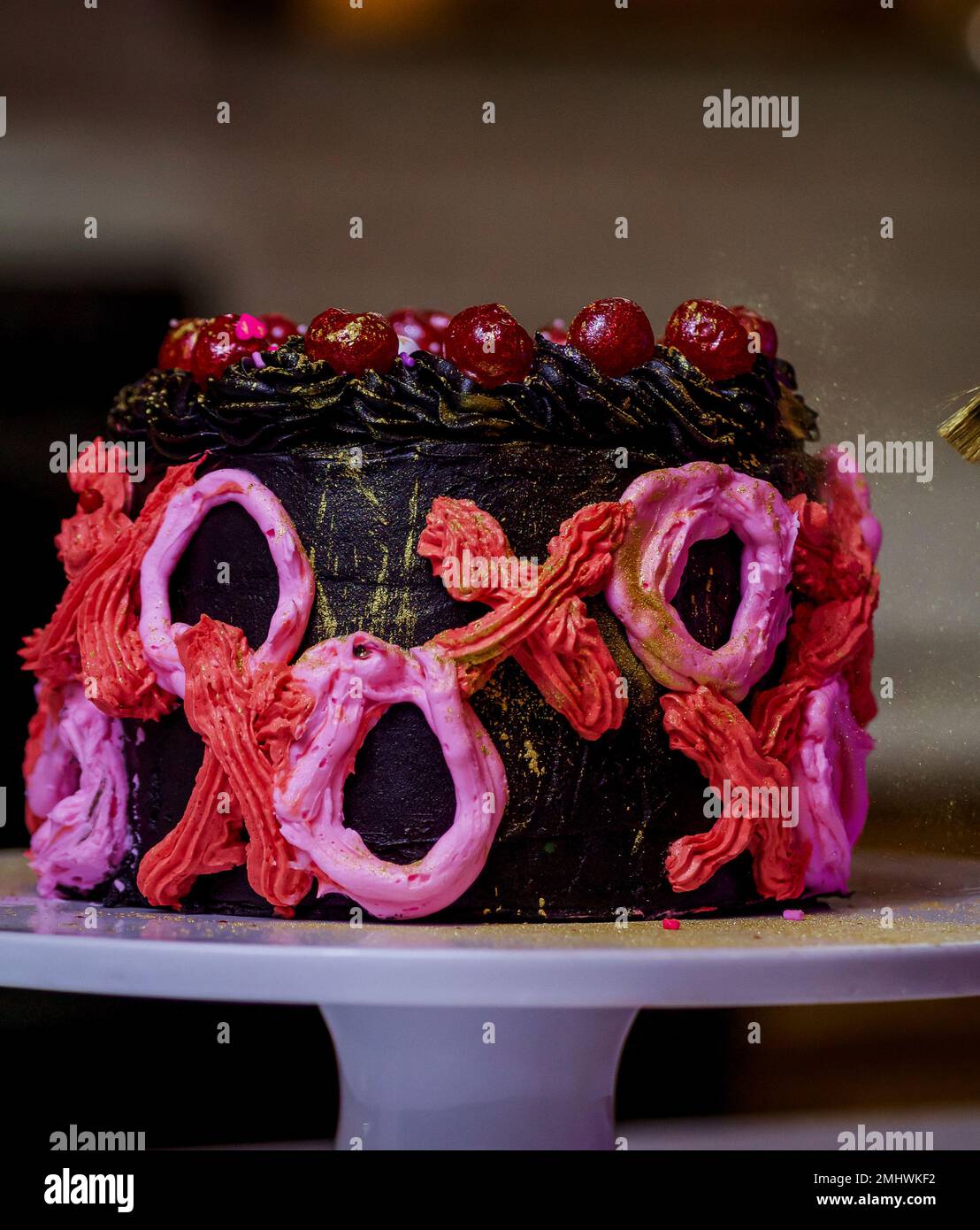 Femme dans sa cuisine de pâtisserie et de décoration d'un gâteau de la Saint-Valentin Banque D'Images