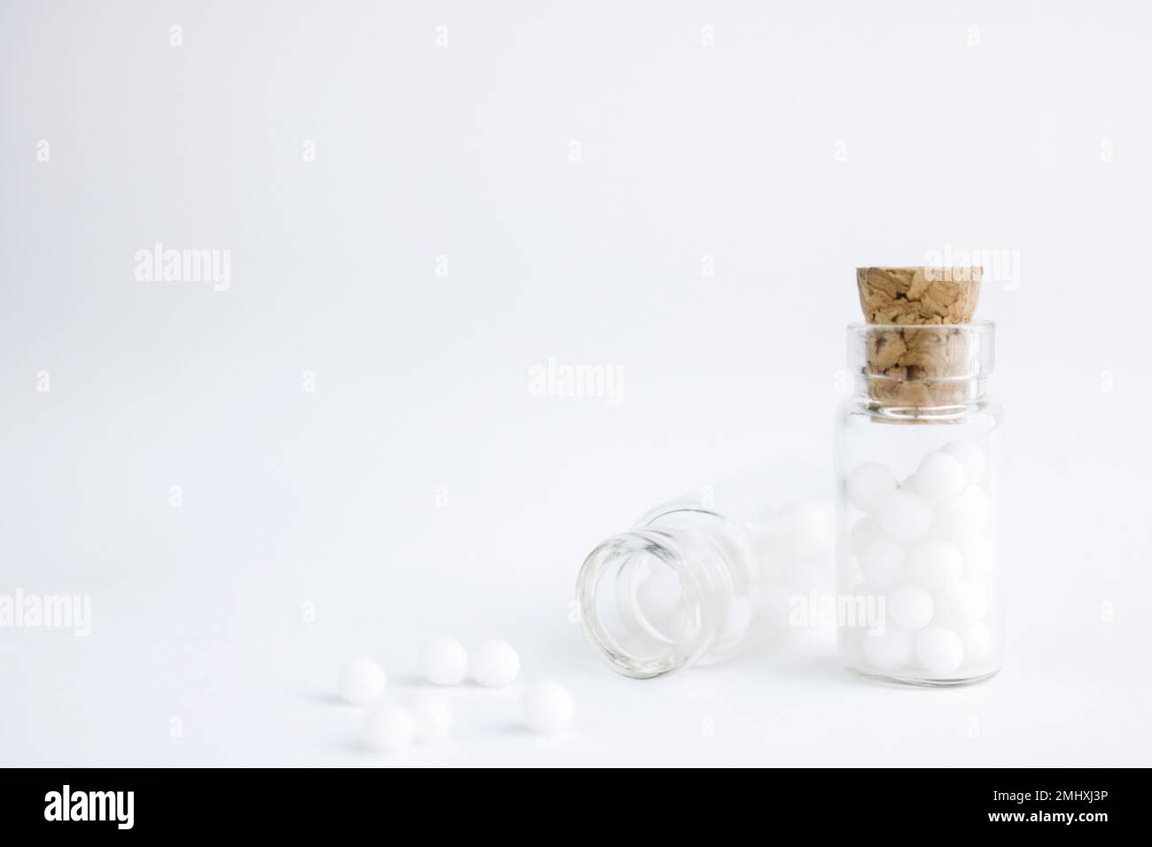 Globules homéopathiques et bouteille en verre sur fond blanc. Alternative homéopathie médecine herbes, soins de santé et pilules. Copier l'espace . Banque D'Images