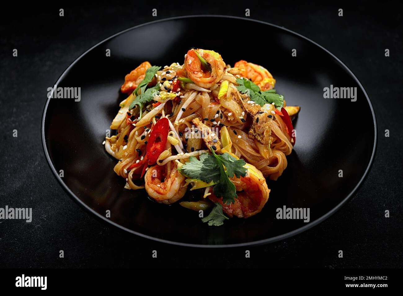 Pâtes avec crevettes et légumes, cuisine asiatique. plaque noire, sur béton gris Banque D'Images