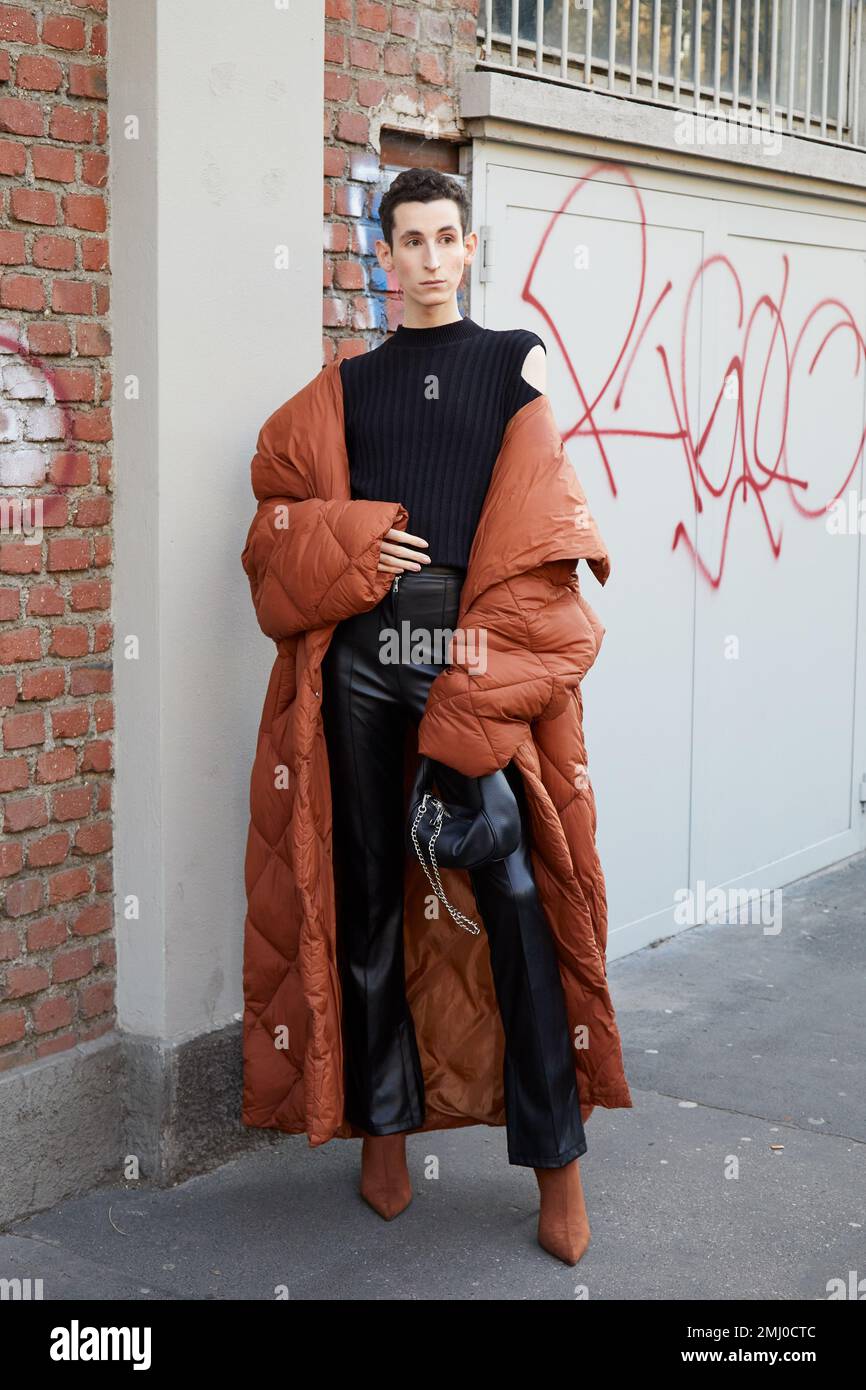 MILAN, ITALIE - 14 JANVIER 2023: Homme avec manteau long rembourré marron et pantalon en cuir noir avant le spectacle de mode Fendi, Milan Fashion week Street style Banque D'Images