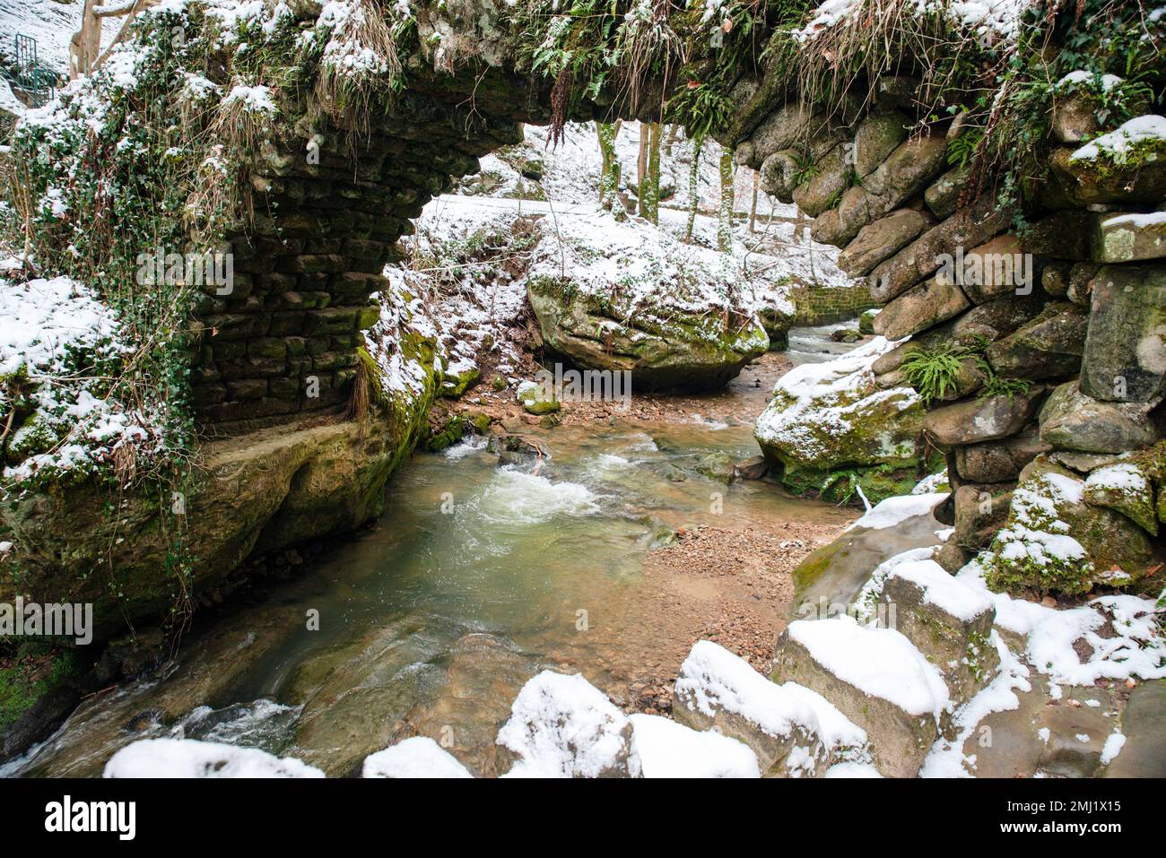 Chute d'eau Scheissendempel, rivière Black Ernz avec pont en pierre recouvert de neige, sentier Mullerthal à Waldbillig, Luxembourg en hiver Banque D'Images