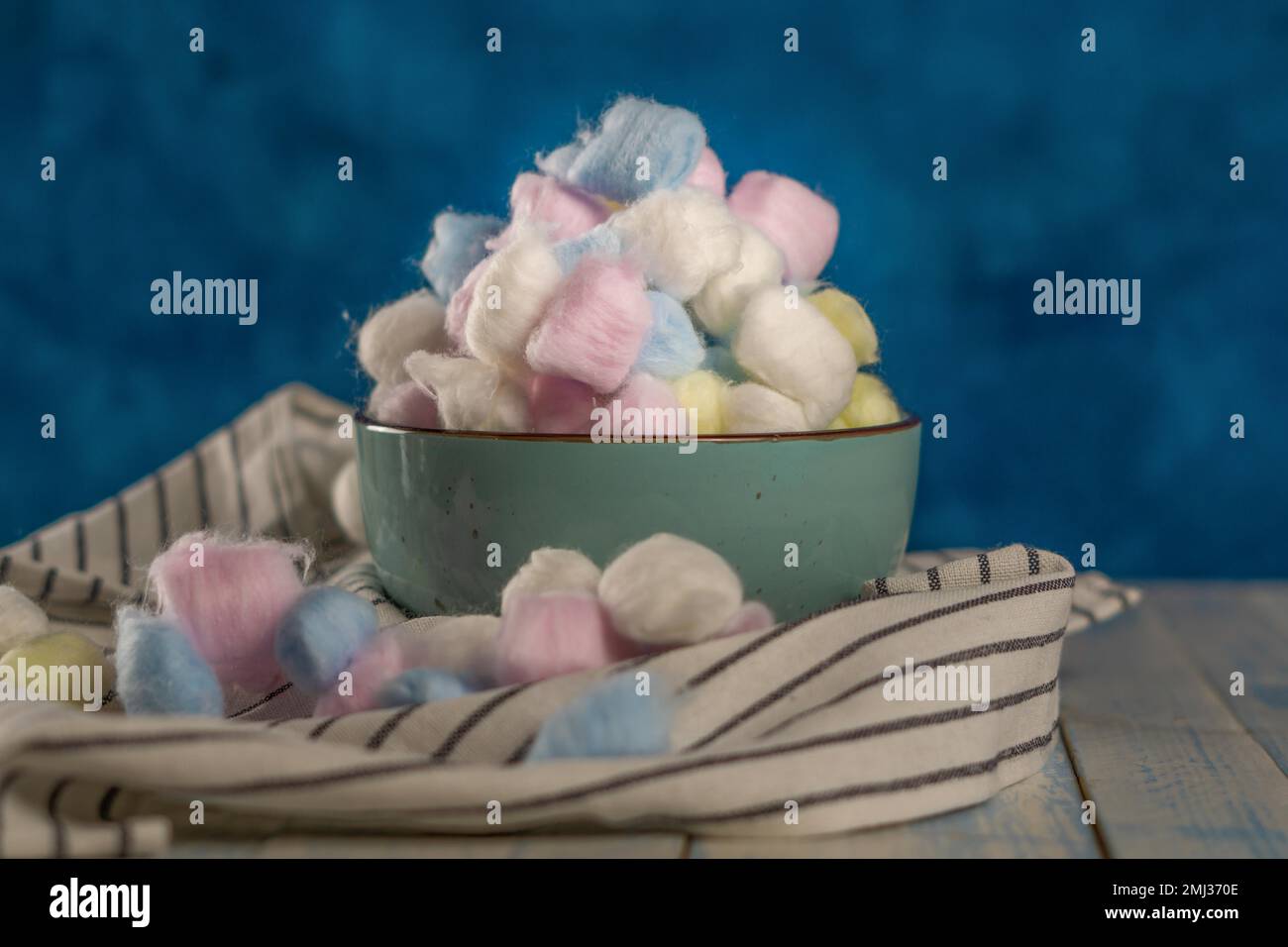 Boules de coton de couleur dans différents récipients sur fond bleu Banque D'Images