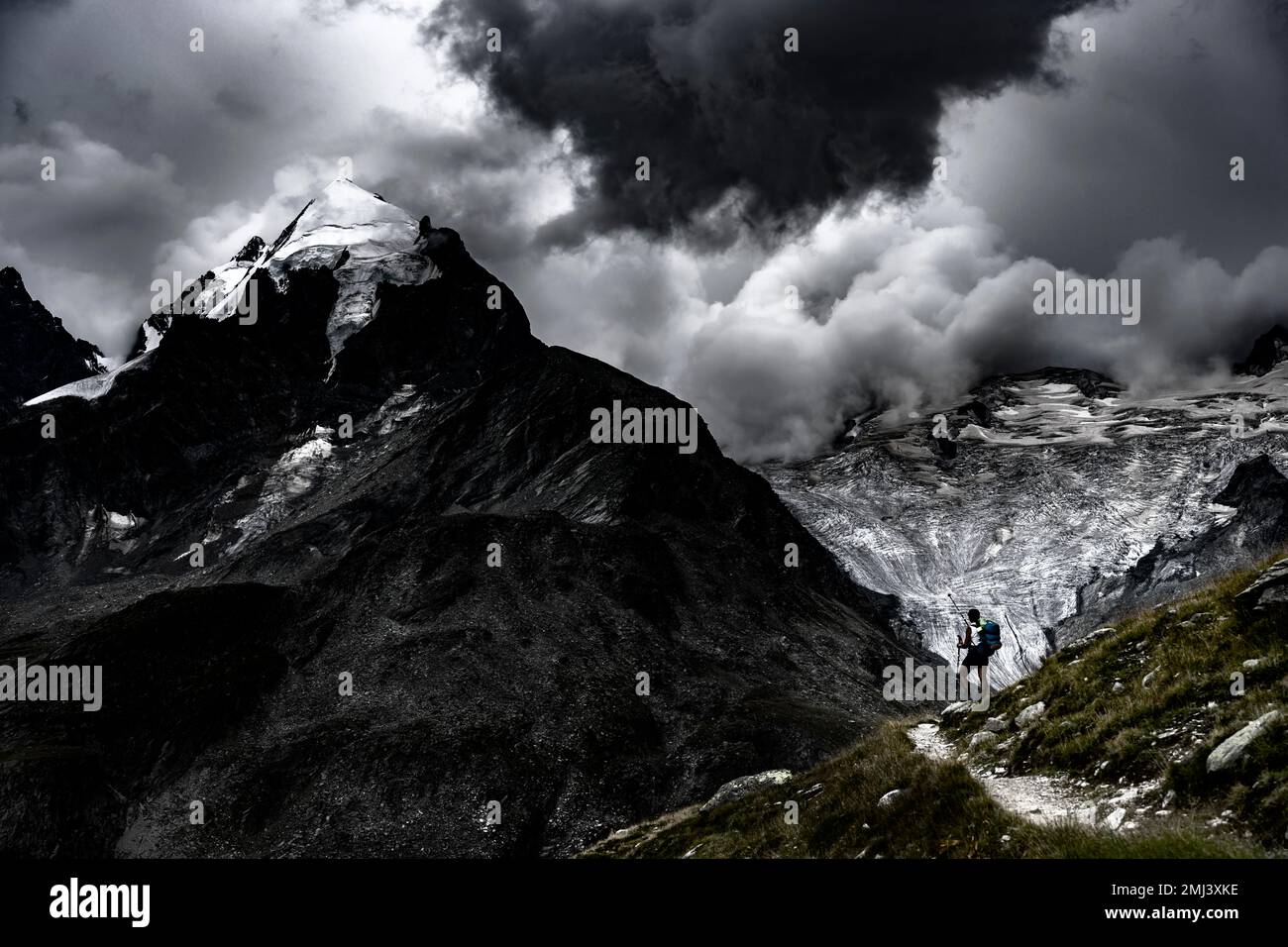 Grimpeurs devant le sommet du groupe Bernina avec des nuages dramatiques, St Moritz, Engadin, Graubuenden, Suisse Banque D'Images