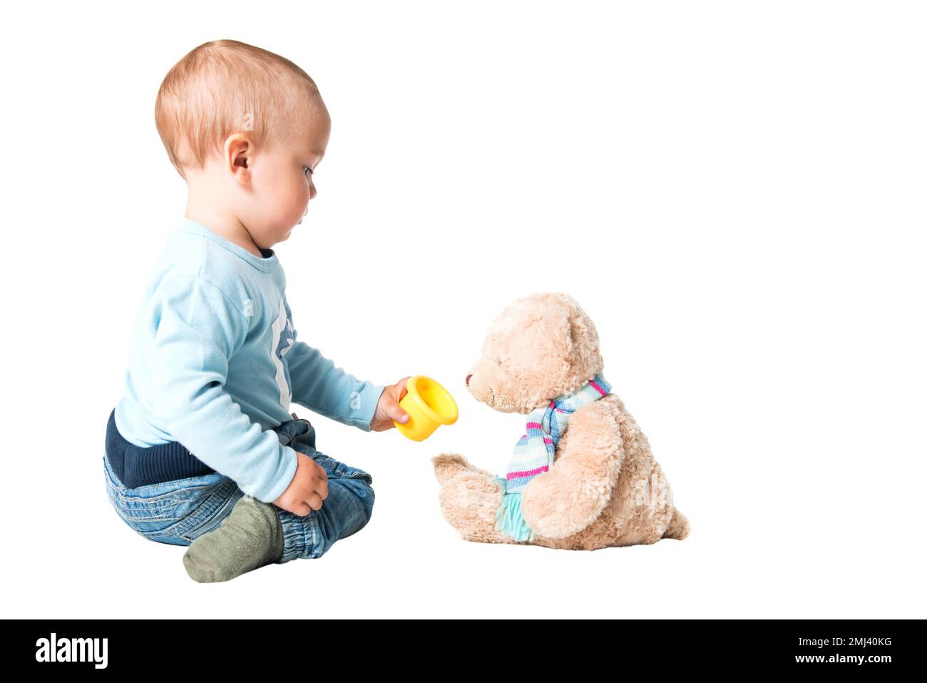Un garçon d'un an nourrissant son ours en peluche, isolé sur fond blanc Banque D'Images