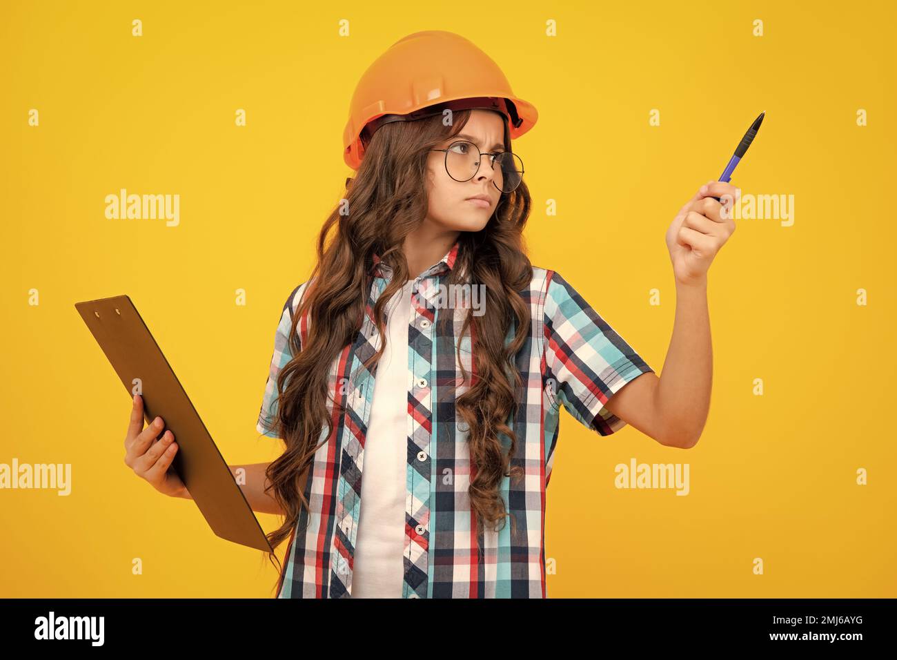 Enfant peintre adolescent dans un casque avec presse-papiers. Enfant dans un casque de sécurité. Un ingénieur enfant sur le chantier. Rénovation et réparation. Intelligent et pensif Banque D'Images