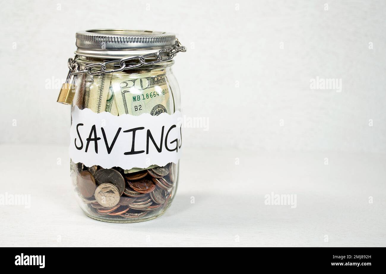 Étiquette d'épargne sur pot Mason rempli de monnaie américaine enveloppée d'une chaîne sécurisée et d'un cadenas Banque D'Images Étiquette d'épargne sur pot Mason rempli de monnaie américaine enveloppée d'une chaîne sécurisée et d'un cadenas Banque D'Images