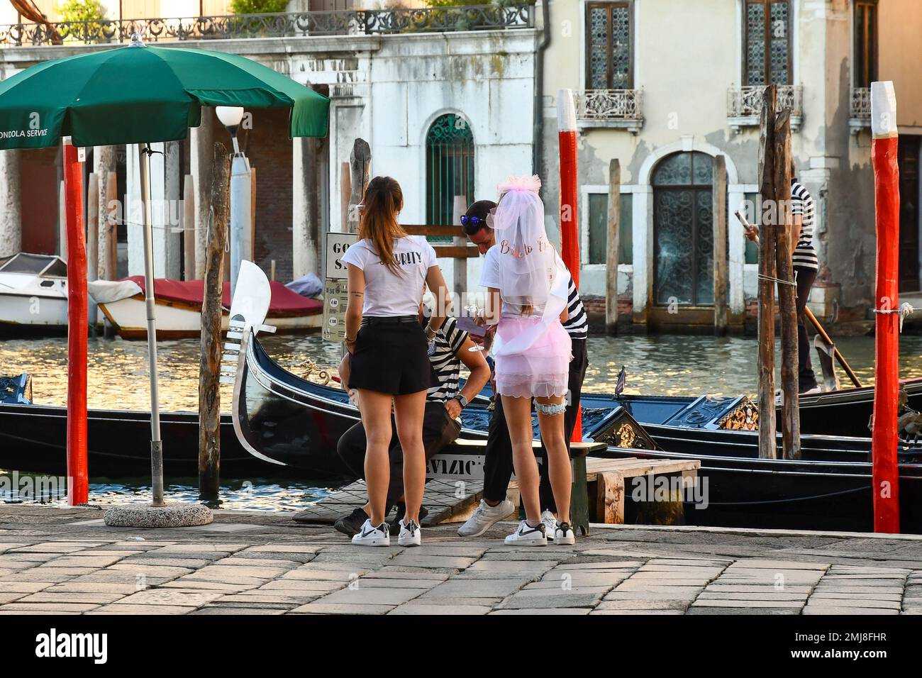 Une mariée à être tente d'impliquer deux jeunes gondoliers à sa fête de bachelorette sur le Grand Canal, Venise, Vénétie, Italie Banque D'Images