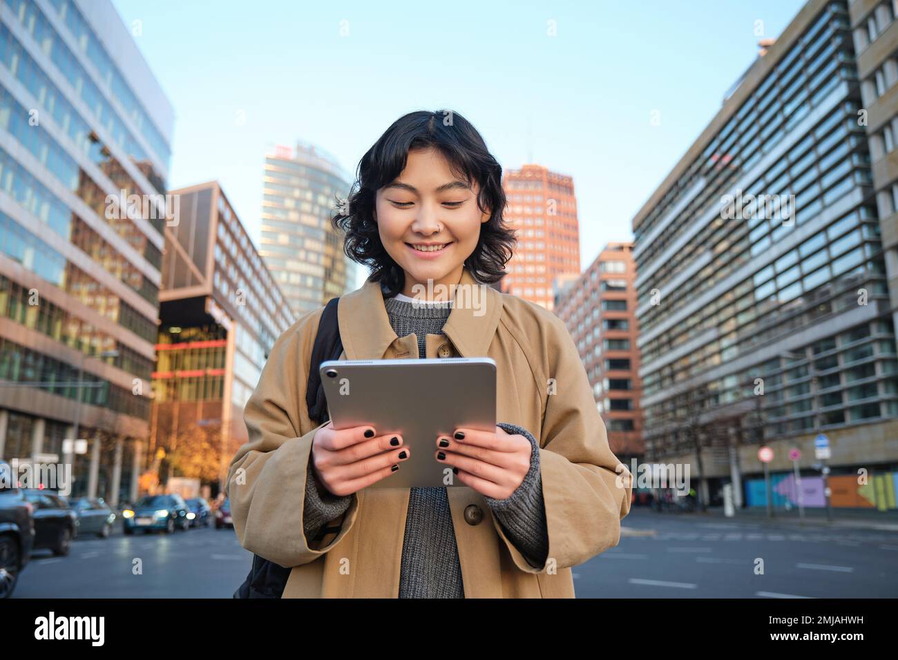 Portrait de sourires de fille coréenne heureux, marche en ville avec tablette numérique et sac à dos, utilise son gadget pour se déplacer Banque D'Images