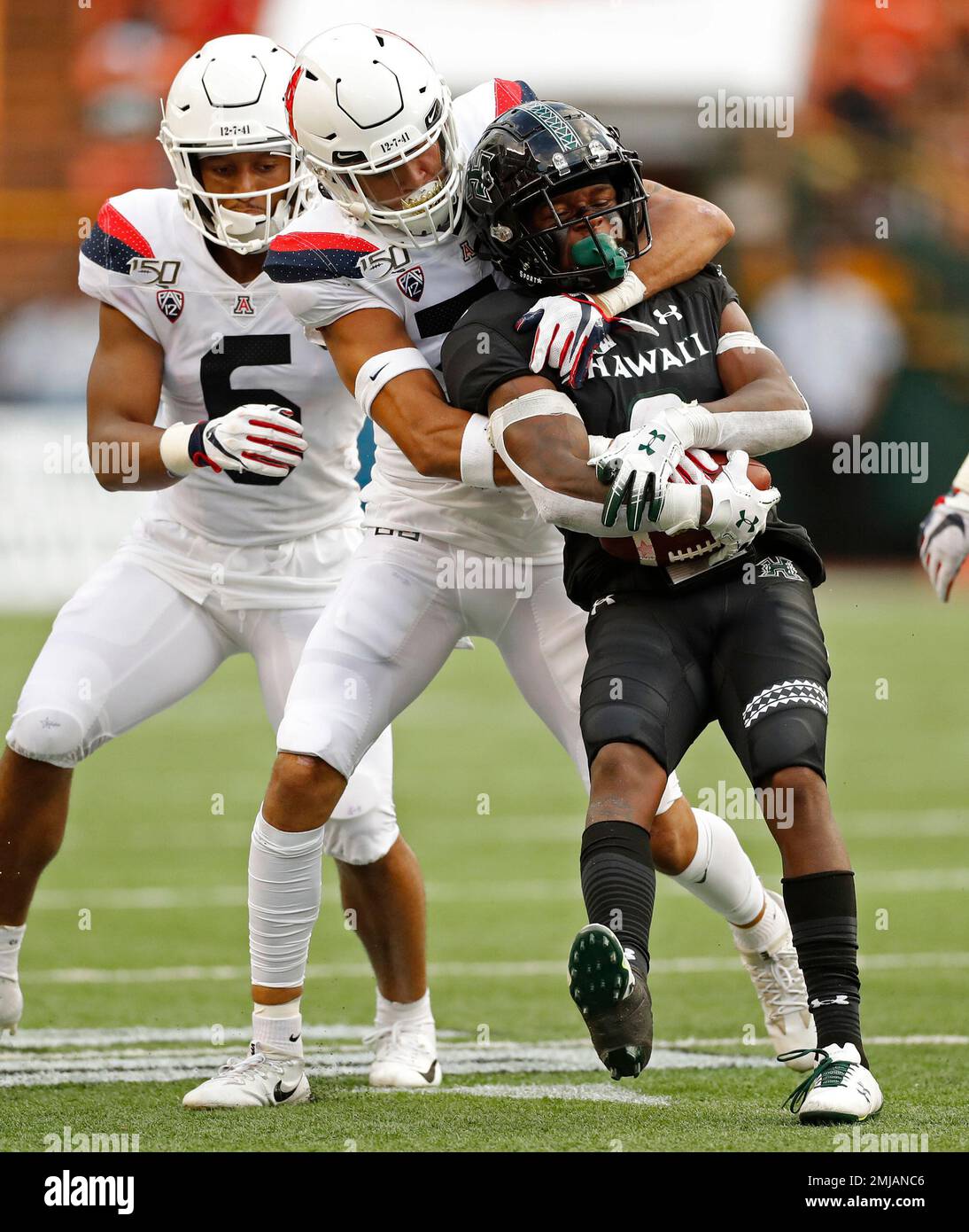 Arizona safety Scottie Young Jr. (6) watches as linebacker Colin Schooler (7) pulls down Hawaii wide receiver Cedric Byrd II (6) during the first half of an NCAA college football game Saturday, Aug. 24, 2019, in Honolulu. (AP Photo/Marco Garcia) Banque D'Images
