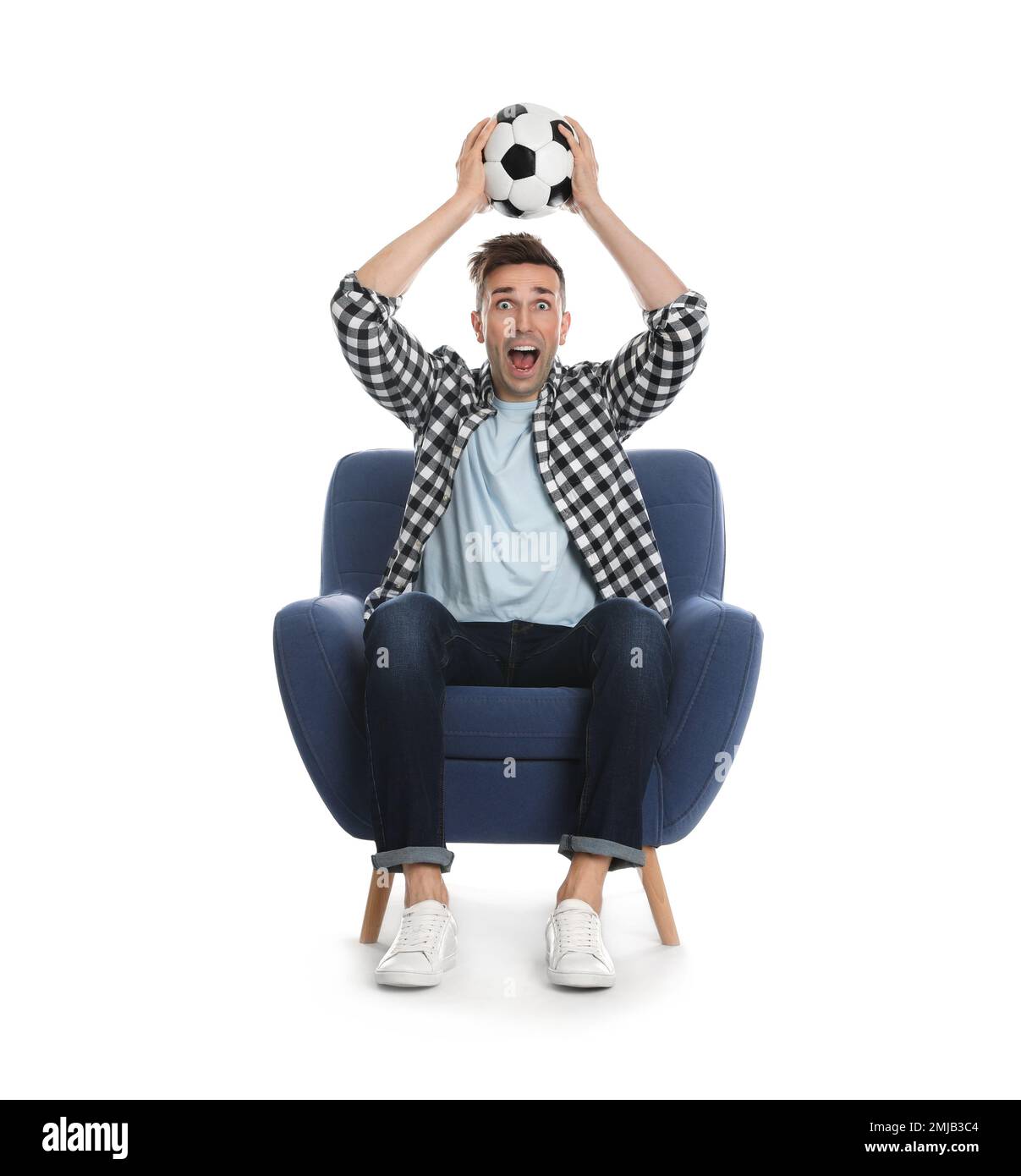 Beau jeune homme assis dans un fauteuil et regardant un match de football sur fond blanc Banque D'Images