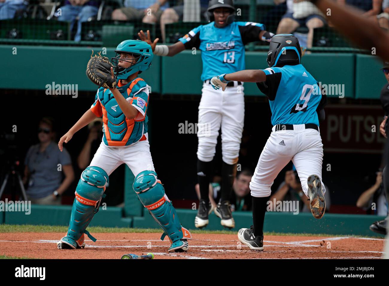 Venezuela's Hendrik Maestre, left, waits for the relay throw as Curacao's Deshandro Tromp (9) and Jurdrick Profar (13) score on a single by Clay Winklaar off Venezuela pitcher Diego Boscan during the first inning of an elimination baseball game at the Little League World Series tournament in South Williamsport, Pa., Tuesday, Aug. 20, 2019. (AP Photo/Gene J. Puskar) Banque D'Images