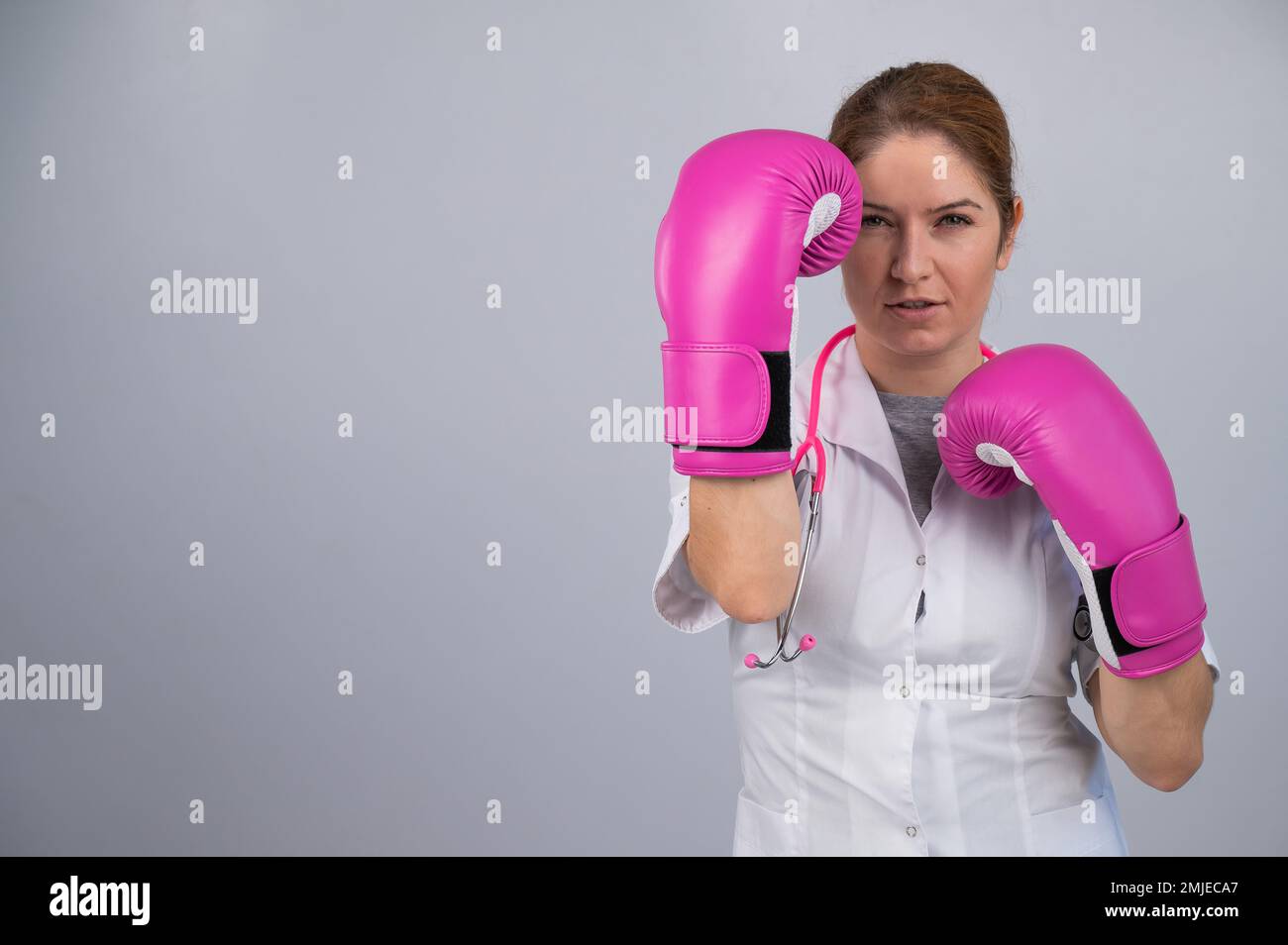 Femme médecin en gants de boxe rose sur fond blanc. Banque D'Images Femme médecin en gants de boxe rose sur fond blanc. Banque D'Images