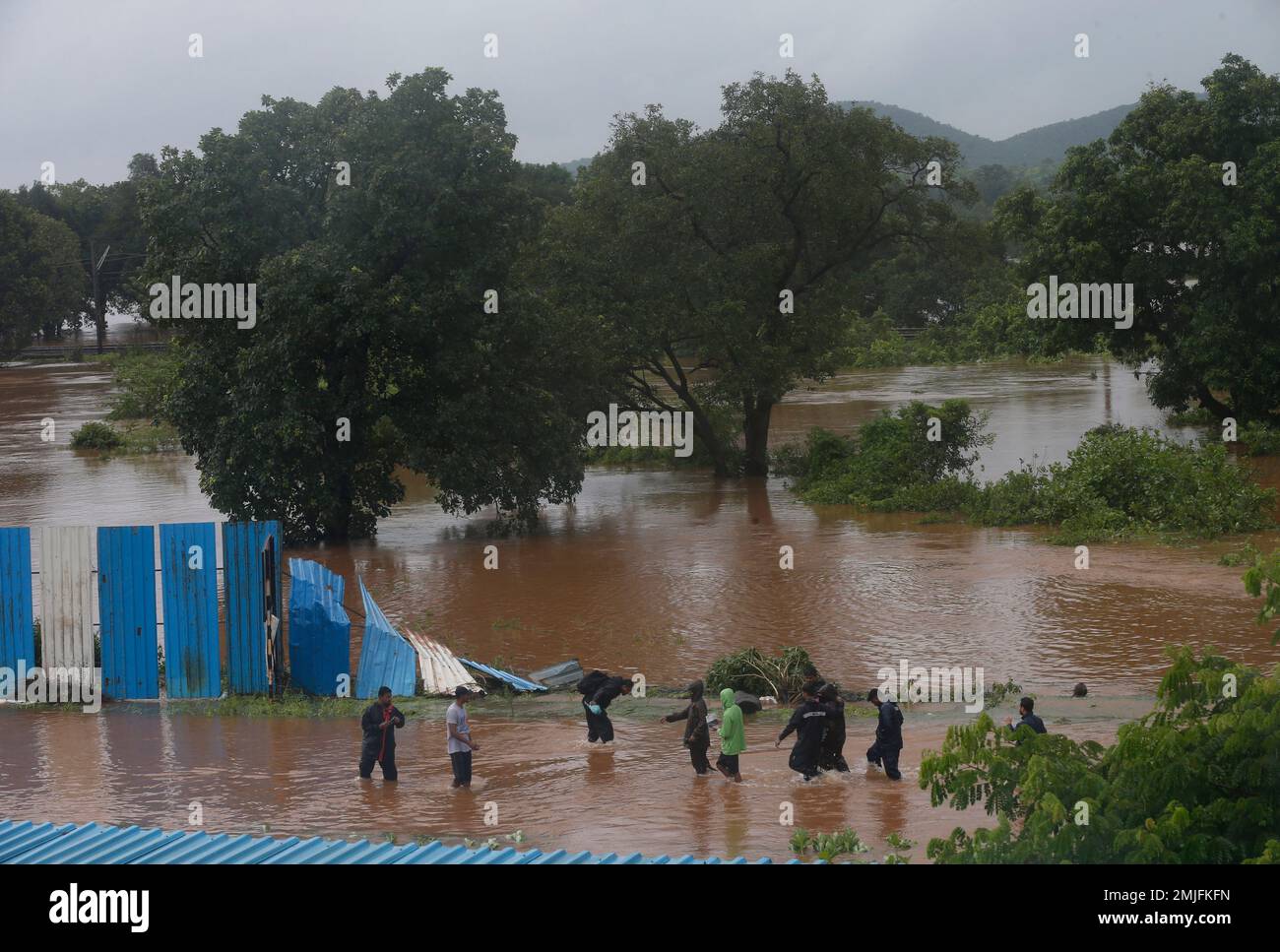 People wade past a waterlogged road in Badlapur, India Saturday, July 27, 2019. Rescuers in India on Saturday safely evacuated all 700 passengers from a train after it got stuck in monsoon floodwaters between two stations near Mumbai, the country's home minister said. A statement by India's disaster management office in Maharashtra state said the Mahalaxmi Express train got stuck due to flooding of the tracks. (AP Photo/Rafiq Maqbool) Banque D'Images
