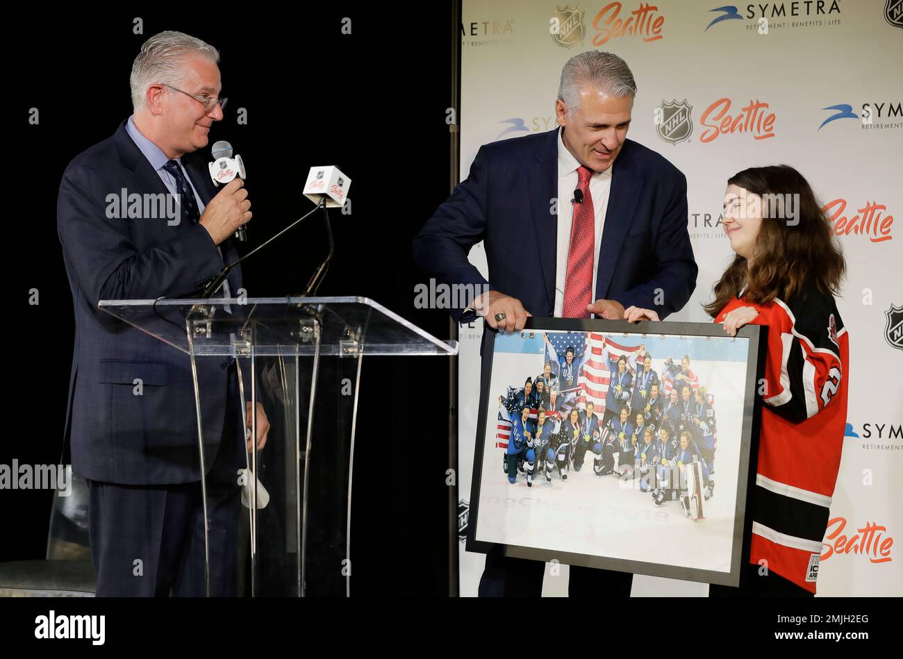 Ron Francis, center, is presented with a photo of the U.S. Women's National Hockey Team by Jaina Goscinski, 12, right, a youth player with the Washington Wild from Redmond, Wash., as Seattle Hockey Partners CEO Tod Leiweke, left, looks on at a news conference, Thursday, July 18, 2019, in Seattle. Francis was introduced Thursday as the first general manager for Seattle's yet-to-be-named NHL hockey expansion team. (AP Photo/Ted S. Warren) Banque D'Images