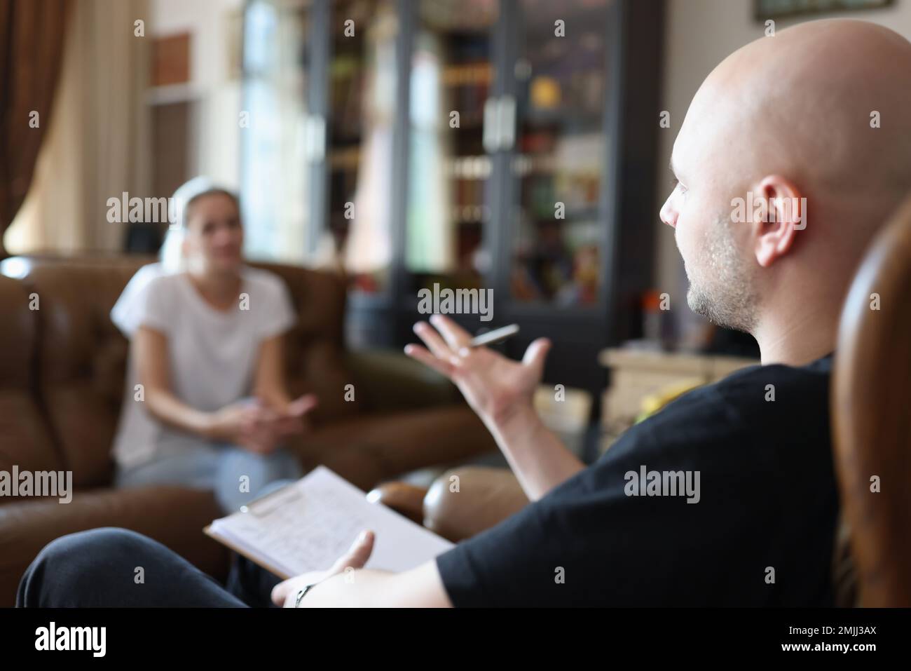 Le psychologue parle au patient tout en étant assis sur une chaise au bureau pendant la séance de psychothérapie. Banque D'Images