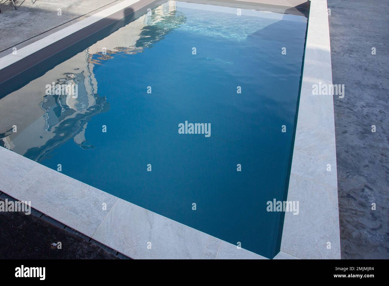 piscine moderne avec pierre, terrasse en béton ciré gris et eau bleue transparente Banque D'Images