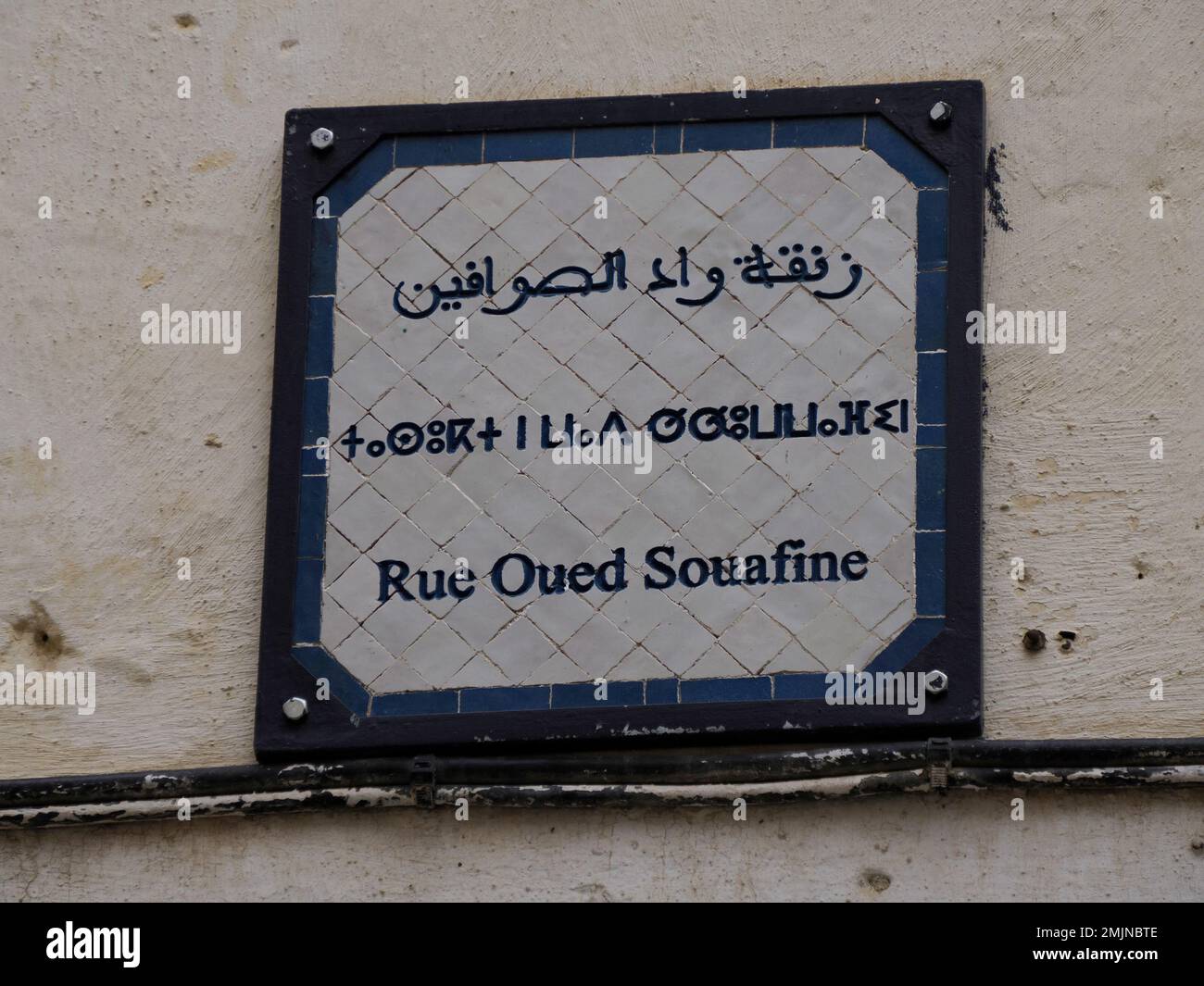 Un petit panneau de rue trilingue arabe français et berbère à Fès médina médiévale (vieille ville). Maroc. Banque D'Images