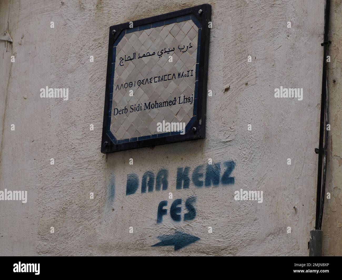 Un petit panneau de rue trilingue arabe français et berbère à Fès médina médiévale (vieille ville). Maroc. Banque D'Images