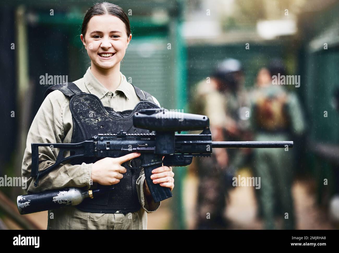 Paintball, heureux et portrait de femme avec un pistolet en uniforme de sécurité pour le jeu de tir extérieur avec le sourire. Une fille de tournoi excitée dans la protection de la veste Banque D'Images