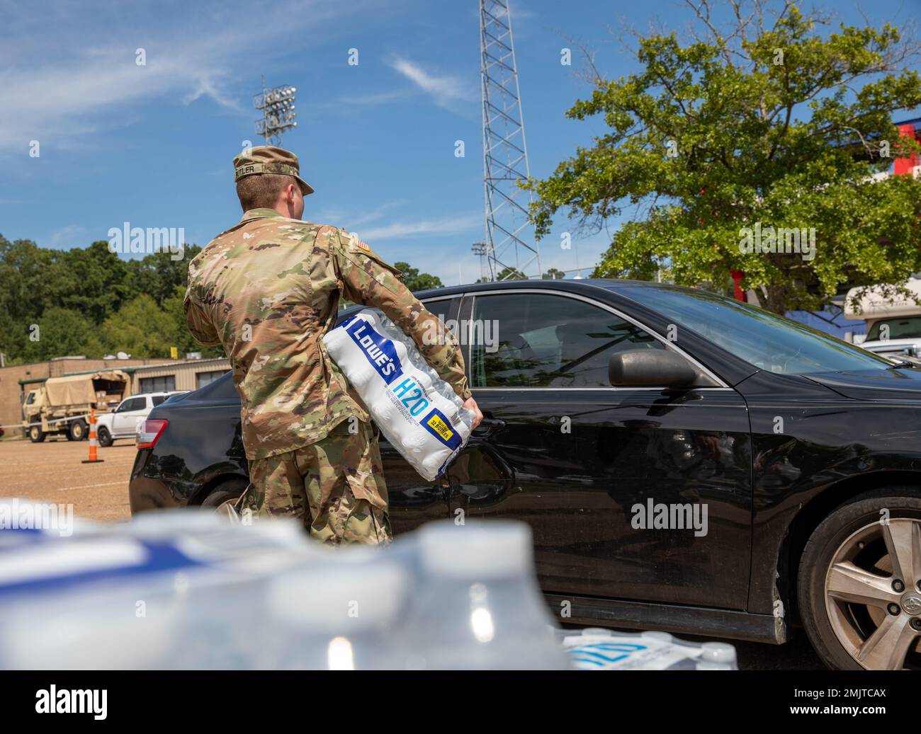 Un soldat avec un commandement de 66th troupes, la Garde nationale de l'armée du Mississippi, met de l'eau dans le siège arrière de la voiture d'une personne au stade Smith-Wills à Jackson, Mississippi, le 1 septembre 2022. Près de 600 gardes nationaux du Mississippi ont été établis sur sept sites de Jackson pour permettre aux résidents de recueillir de l'eau embouteillée et de l'eau non potable des camions d'eau pour aider à soulager certains effets de la crise de l'eau de Jackson. (É.-U. Photos de la Garde nationale de l'armée par le sergent d'état-major. Connie Jones) Banque D'Images