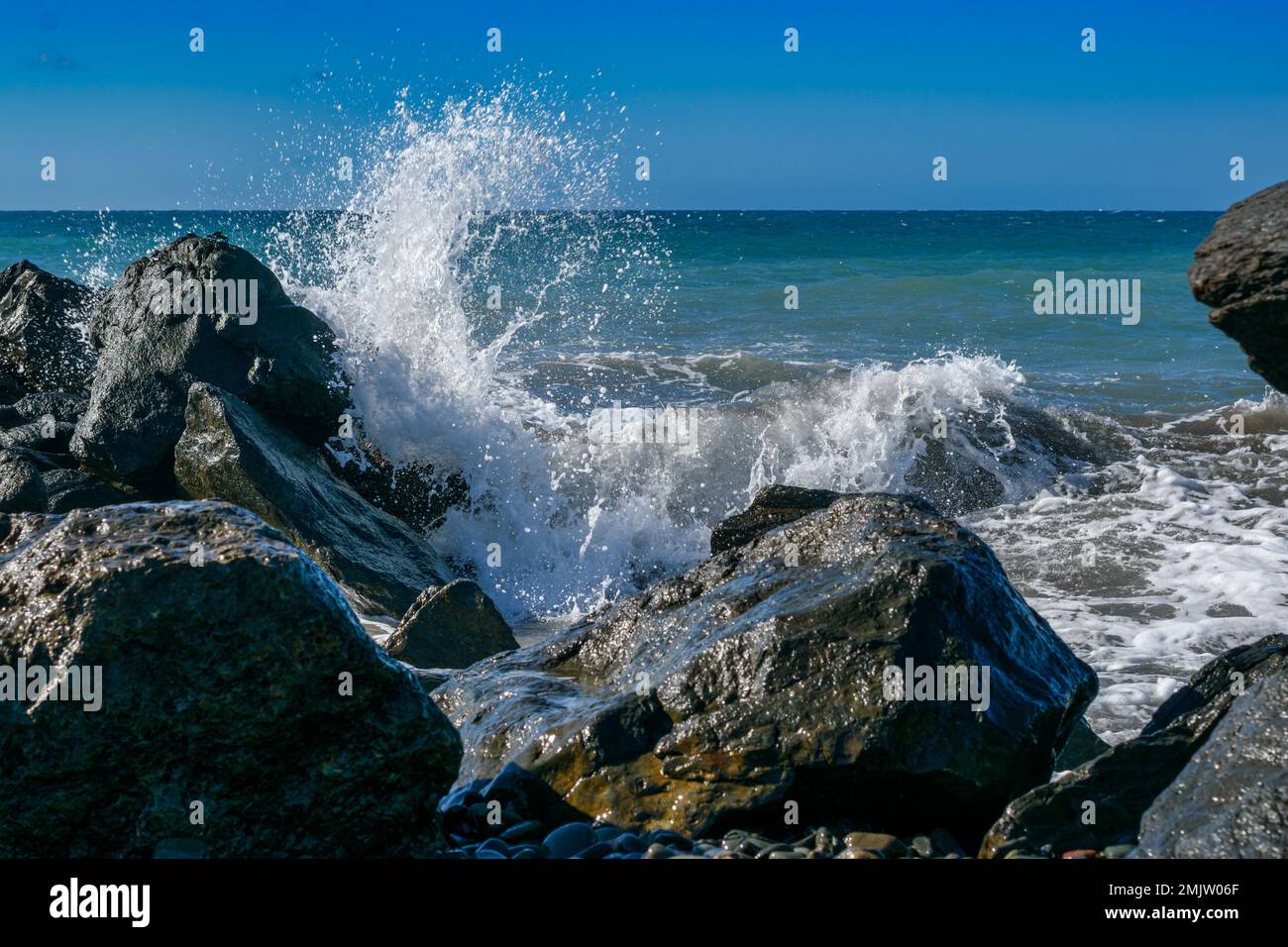 Une grosse vague éclabousse dans les rochers de l'eau sauvage agitée de l'océan Atlantique Banque D'Images