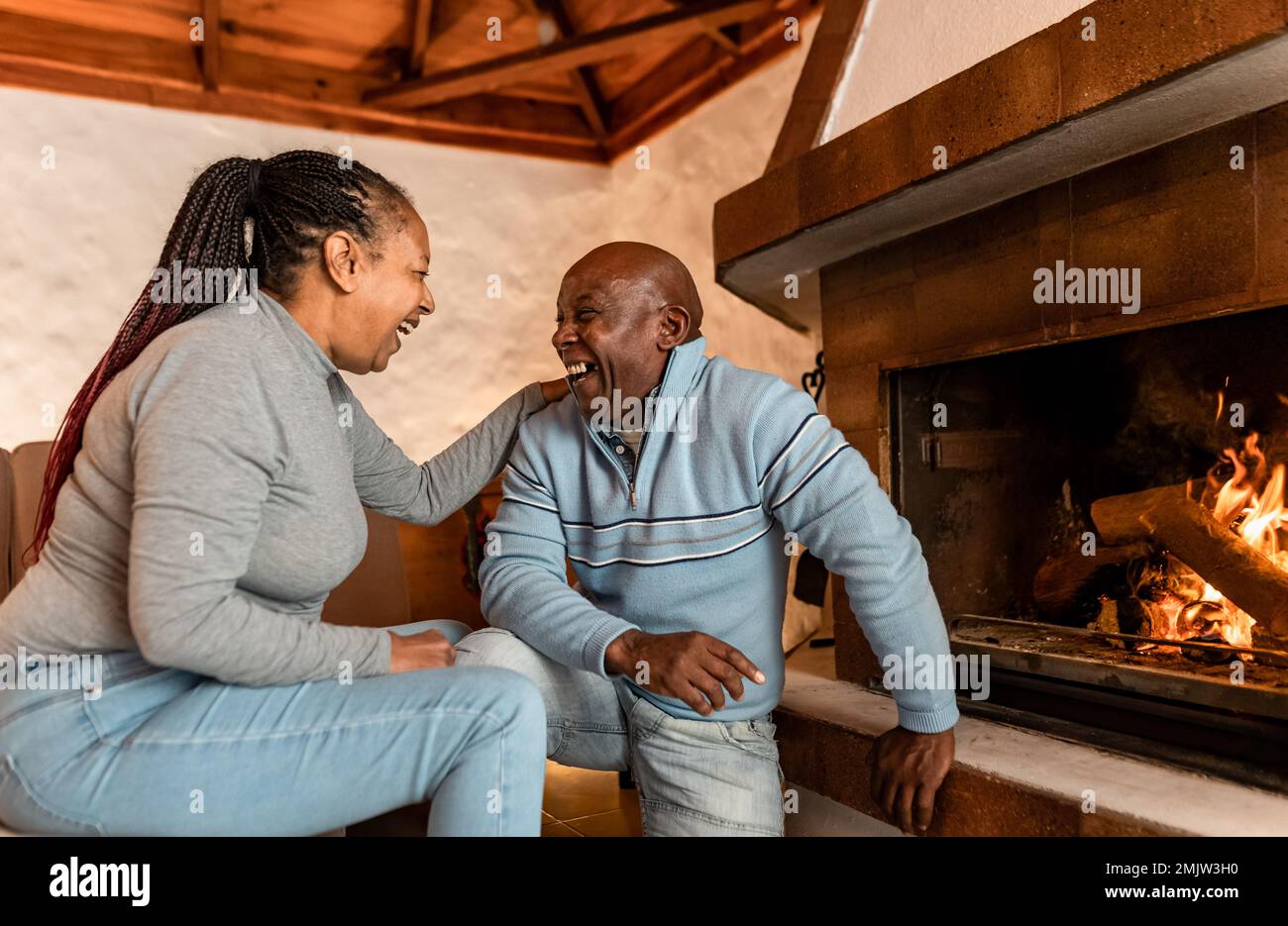 Heureux couple senior debout ensemble près de la cheminée dans leur maison rustique Banque D'Images