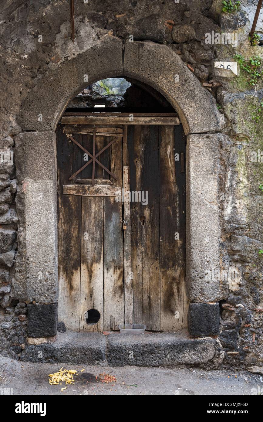 Une vieille porte d'une maison construite à partir de lave dans les rues médiévales de Bronte, Sicile (avec des pâtes et des biscuits pour chats mis en place pour les nombreux chats errants) Banque D'Images