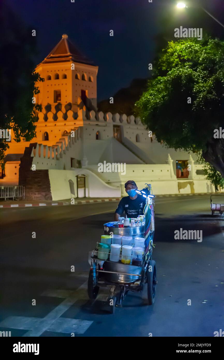 Un vendeur de nourriture de rue marchant sur la route Phra Athit la nuit, avec le fort Phra Sumen en arrière-plan, Bangkok, Thaïlande Banque D'Images