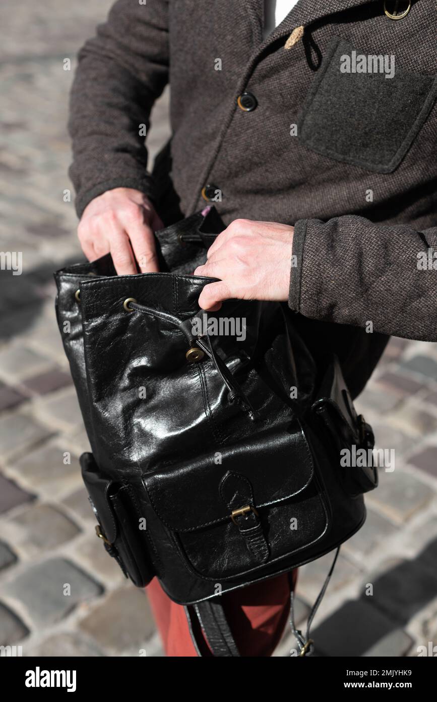Photo d'un homme avec un sac à dos en cuir noir avec un look ancien et rétro. Photo à l'extérieur Banque D'Images