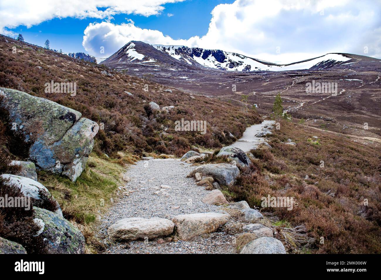 Sentier de randonnée courbé, parc national de Cairngorms, Scottish Highlands, Écosse, zone populaire de randonnée et de ski. Sommets enneigés, ciel bleu, rochers. Banque D'Images