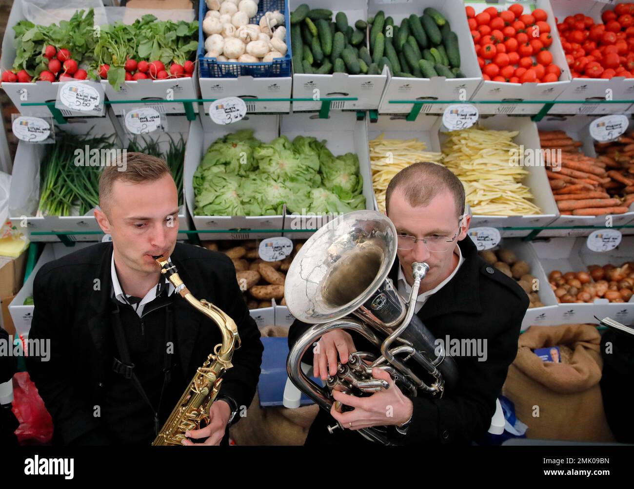 A brass band plays, back dropped by vegetables on sale, at a food market in the Transylvanian town of Sibiu, Romania, Friday, May 10, 2019. (AP Photo/Vadim Ghirda) Banque D'Images