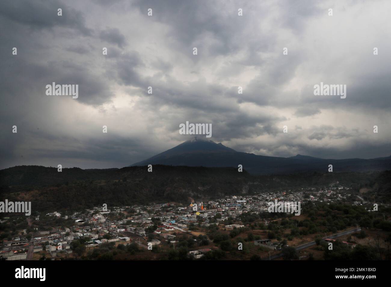 This Thursday, May 2, 2019 photo shows a view of the Mexican village Santiago Xalitzintla as the looming Popocatepetl volcano spews ash. Santiago Xalitzintla has the distinction of being the community closest to Popocatépetl, a crater that has increasingly been belching lava and spewing ash as far as Mexico City, 90 kilometers (56 miles) to the northwest. (AP Photo/Marco Ugarte) Banque D'Images