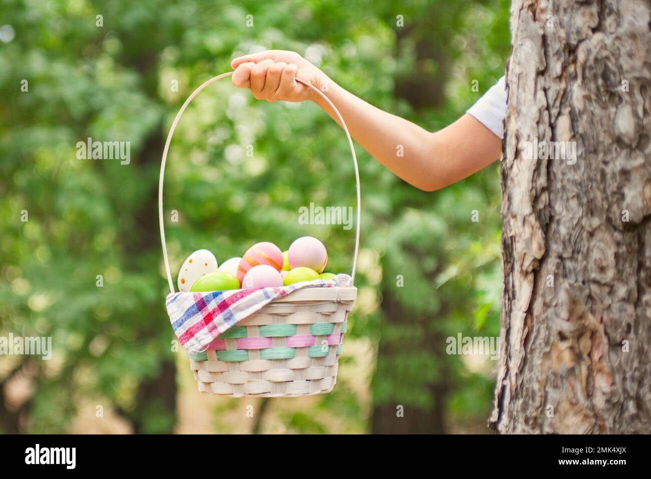 Un panier de main d'enfant rempli d'œufs de pâques colorés après la chasse aux œufs Banque D'Images