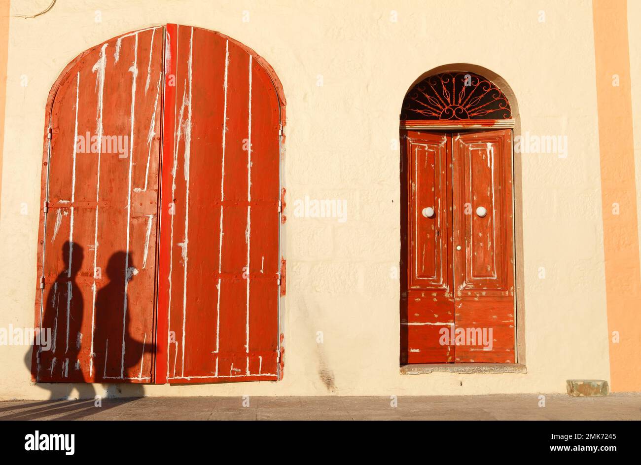 Personnes jetant des ombres sur les portes rouges, village de pêcheurs de la baie de Xlendi, Gozo, îles maltaises Banque D'Images