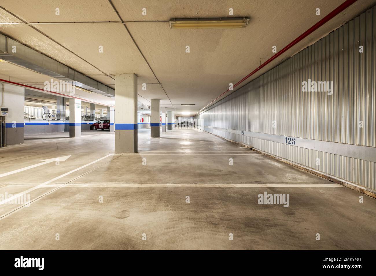 Garage d'un immeuble résidentiel avec les espaces délimités par la peinture blanche et les murs couverts de plaques métalliques Banque D'Images