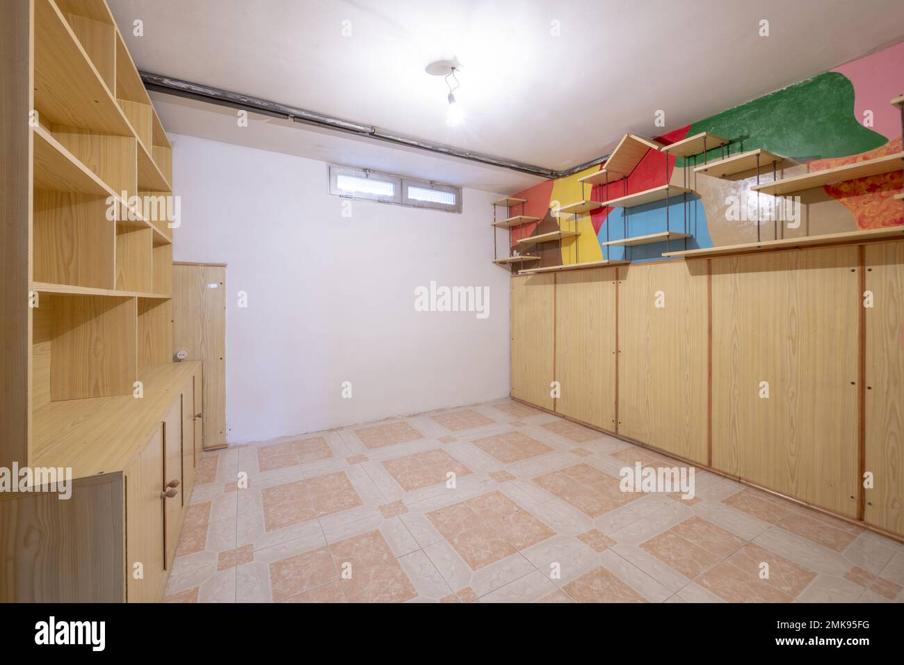 Chambre vide avec armoire intégrée et bibliothèque de même matériau, petites fenêtres et sols en grès Banque D'Images