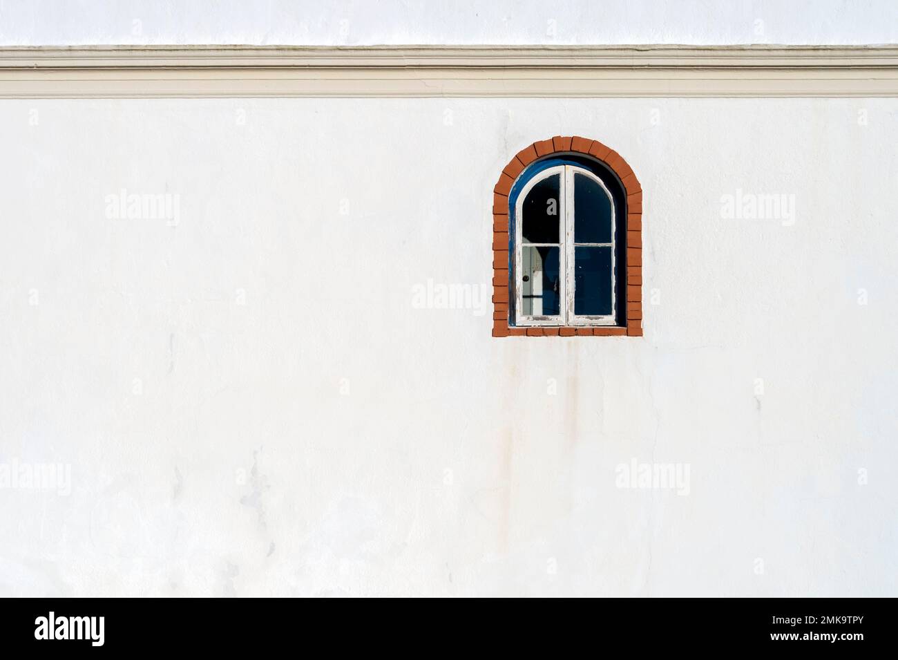 Ancien bâtiment avec une fenêtre voûtée sur un mur de rendu blanc. Banque D'Images