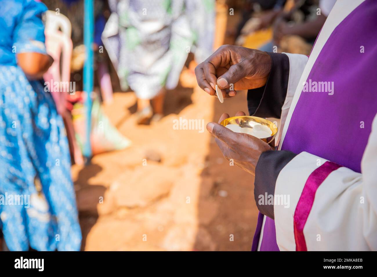 Gros plan des mains d'un prêtre africain qui est sur le point de donner le pain sacramentel aux croyants Banque D'Images