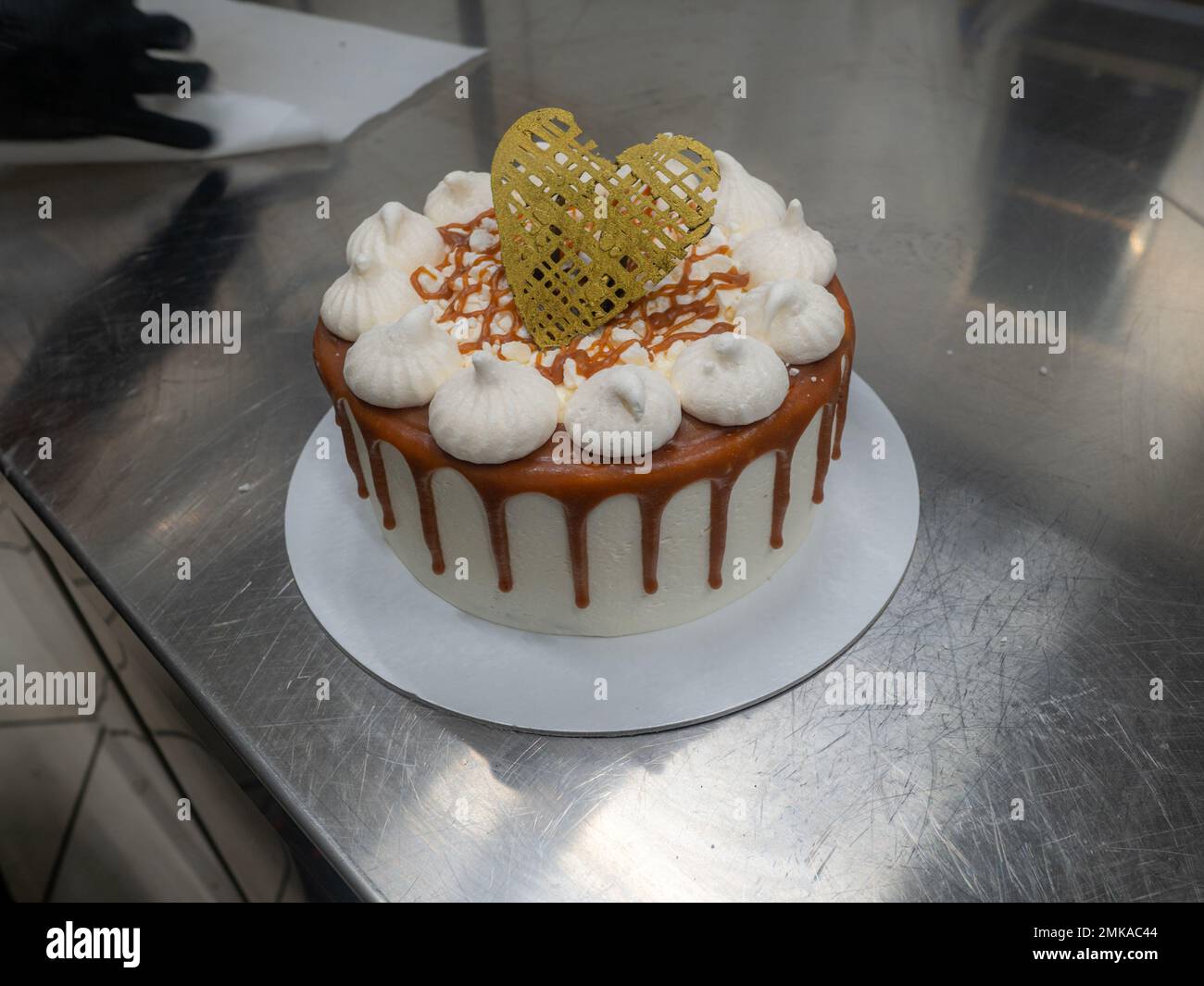 pâtissière de chef finissant des gâteaux dépoli au caramel salé avec des meringues et un surmatelas fait main au coeur doré chocolat Banque D'Images