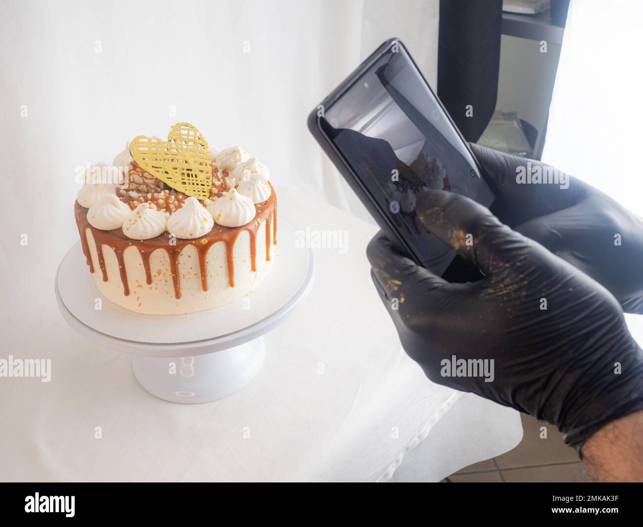 boulanger chef confectionner un rouleau de gâteaux dépoli au caramel salé avec des meringues et un surmatelas en coeur de chocolat avec photo de smartphone Banque D'Images