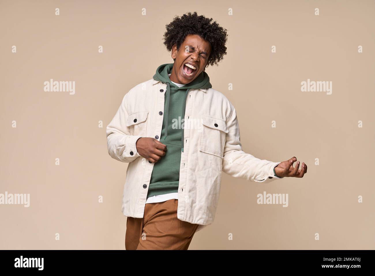 Fou funky Afro-américain gars prétendant jouer de la guitare isolée sur beige. Banque D'Images