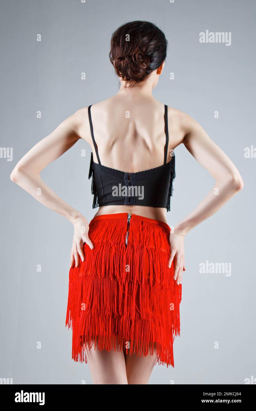 Une danseuse élégante interprète une danse latino-américaine dans une élégante robe rouge ornée de bijoux étincelants. Mode et beauté. Spectacle de ballet. Portrait de studio Banque D'Images