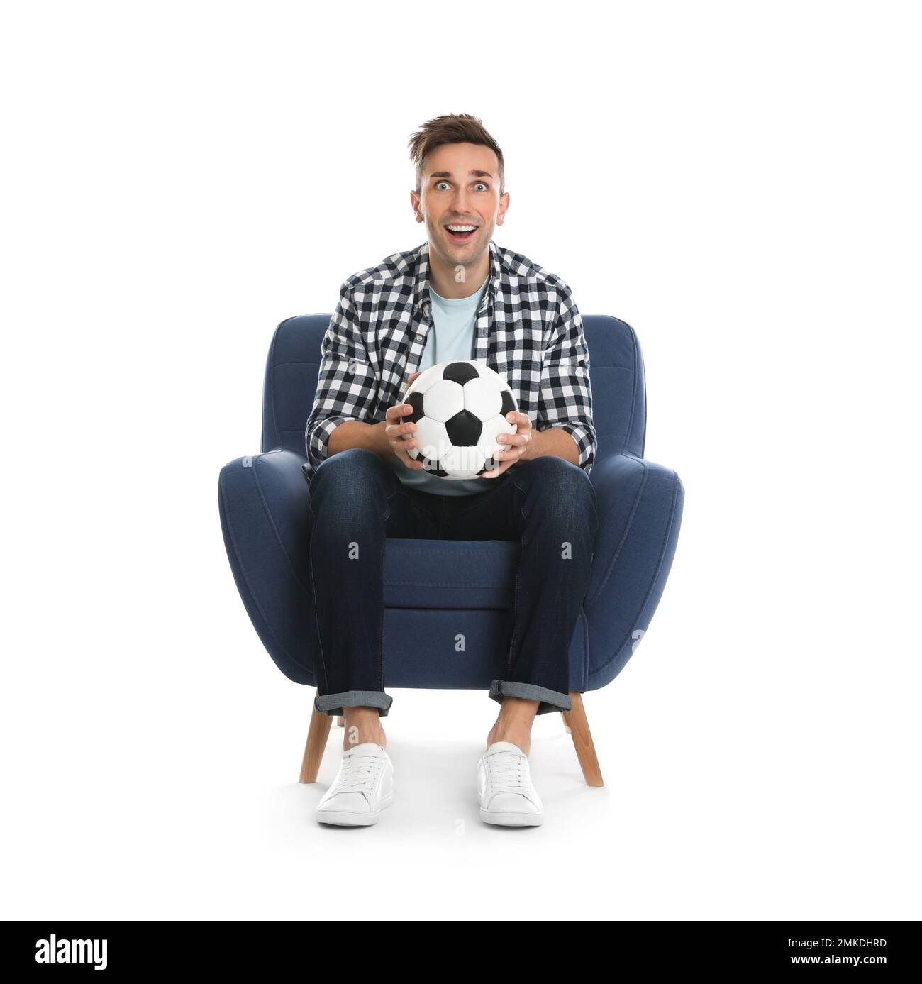 Beau jeune homme assis dans un fauteuil et regardant un match de football sur fond blanc Banque D'Images