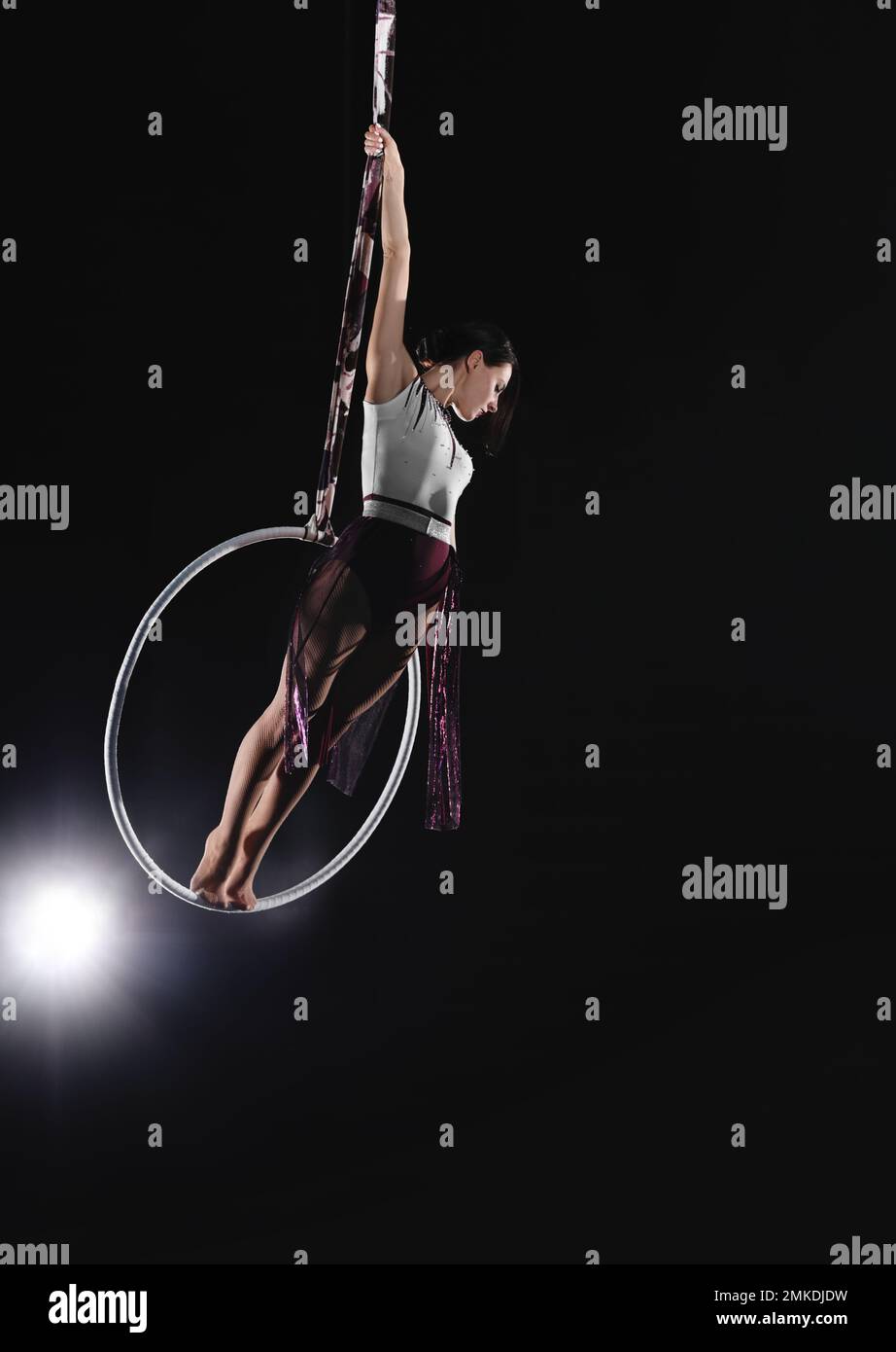 Jeune femme exécutant un élément acrobatique sur un anneau aérien à l'intérieur Banque D'Images