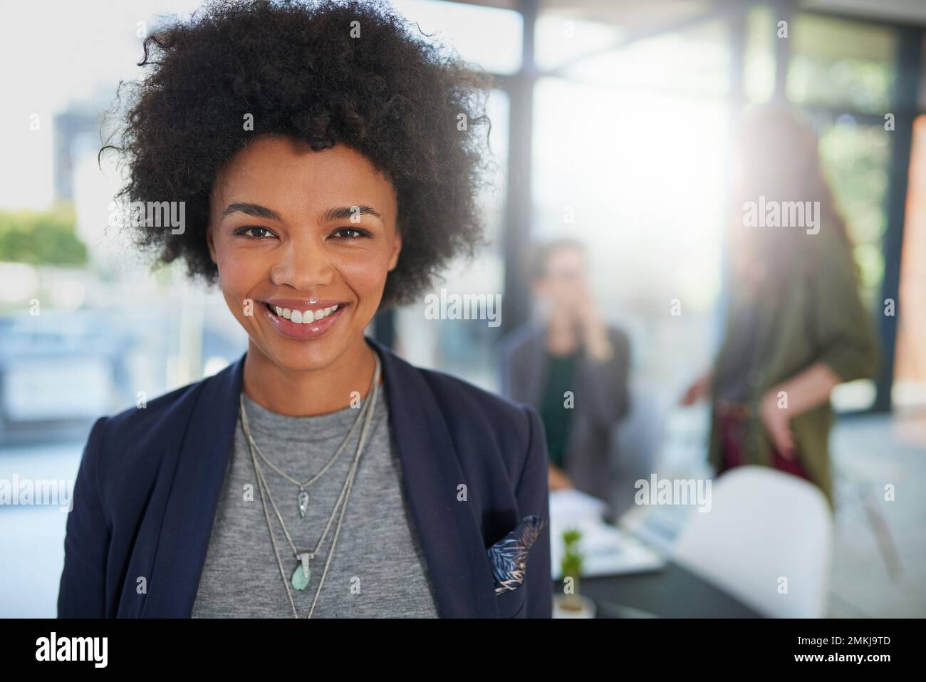 Mettez vos vues sur rien de moins que la grandeur. Portrait d'une jeune création debout dans un bureau avec des collègues en arrière-plan. Banque D'Images