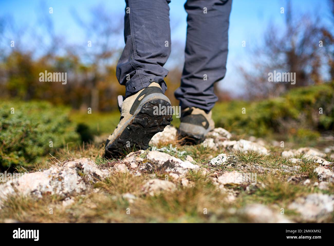 Jambes d'un randonneur dans des bottes de trekking marchant dans les montagnes gros plan. Pieds de touristes marchant portant des chaussures de randonnée sur une route rocheuse capturée de Banque D'Images