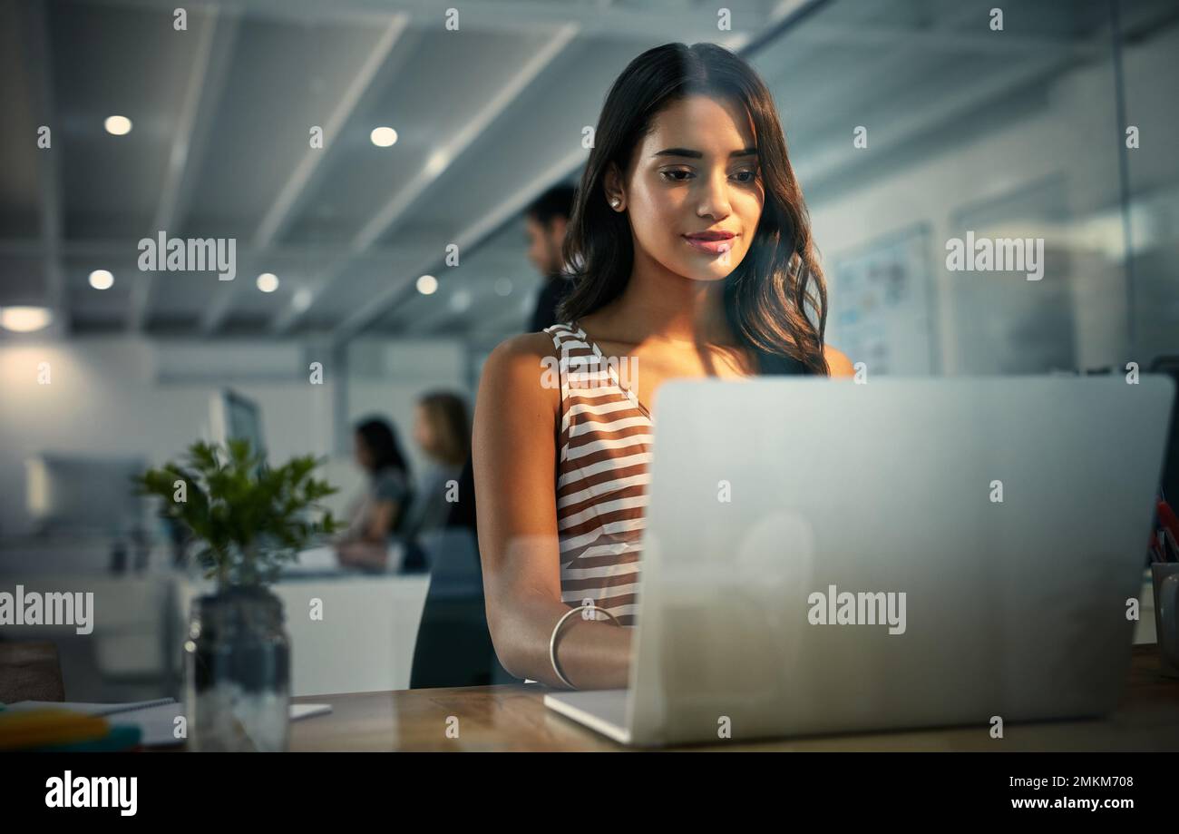 Des heures de travail acharné. femme d'affaires utilisant un ordinateur portable pendant un quart de travail tardif. Banque D'Images