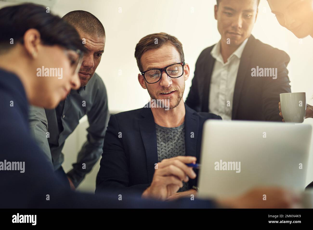 Travailler en équipe pour un meilleur produit final. un groupe de collègues discutant de quelque chose sur un ordinateur portable pendant une réunion. Banque D'Images